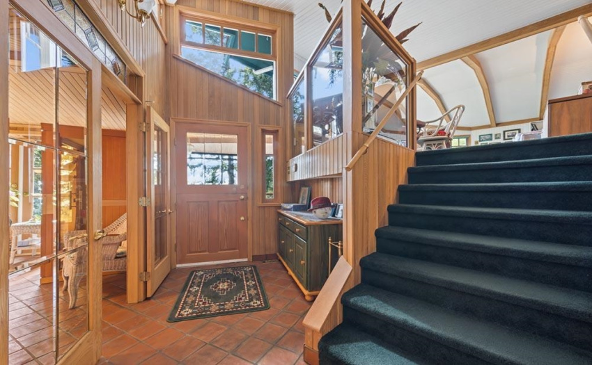 A welcoming entrance hall enjoys high ceilings and is flooded with natural light beaming through angled custom designed windows.