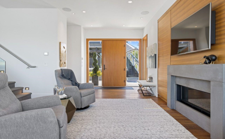 Open concept foyer looks across to the view.   Walnut cabinetry with hidden storage beside fireplace and custom concrete mantel.