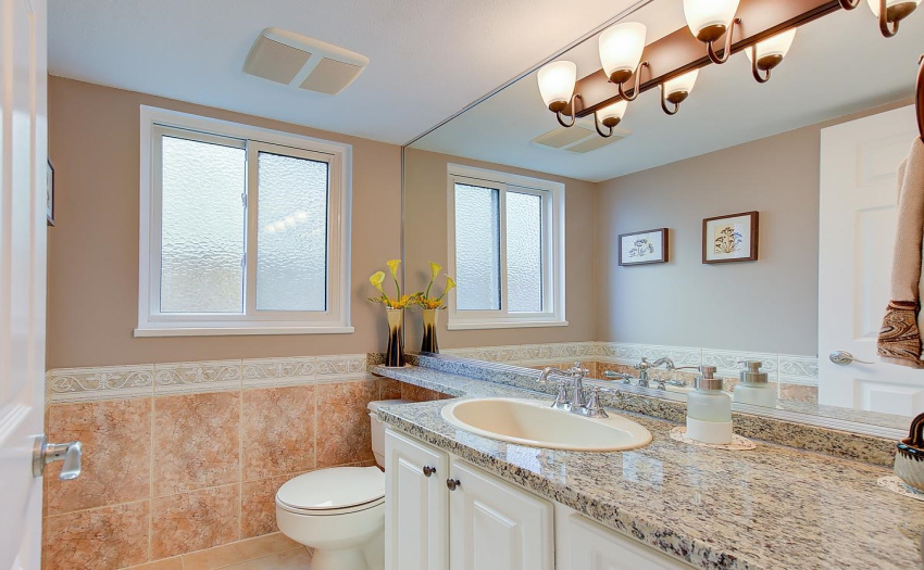 This powder room welcomes your guests as they admire the elegant pastel colours, and granite countertop and extra long mirror.