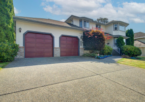 Mature landscaping frame this house with a double garage and lots of parking in the driveway.
